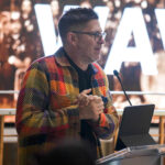 USC Annenberg School for Communication and Journalism Professor and USC vice provost for the arts, Josh Kun, speaks at a PopCon lectern inside the Annenberg building on USC's campus.