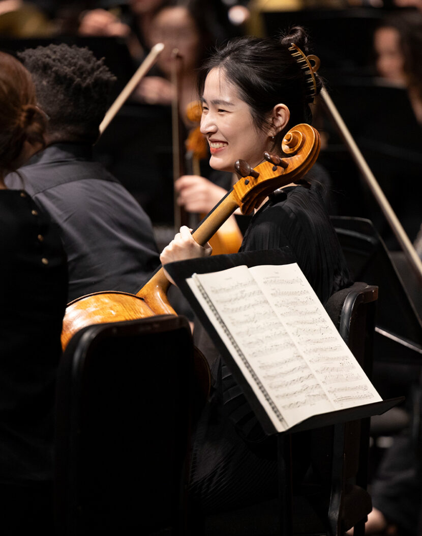 Photo of violin player in concert dress on stage.