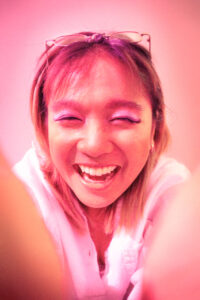 Photo of a smiling person in pink light.