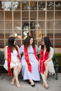 Photo of smiling college graduates wearing ceremonial sashes.