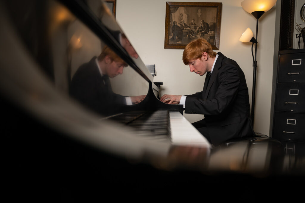Photo of a pianist performing at their instrument indoors.