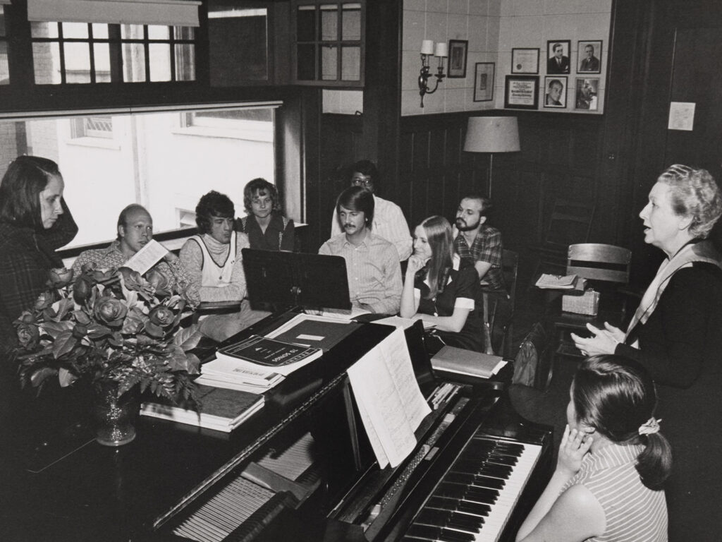 A black and white photo of a piano classroom at a college in the 1980s.