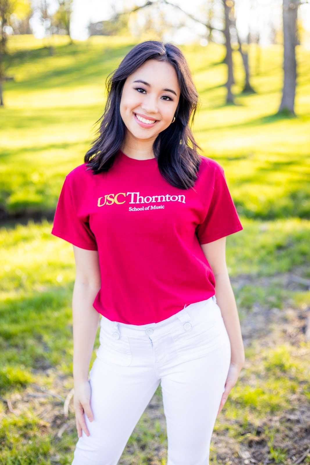 A smiling college student outdoors wearing a red shirt. 