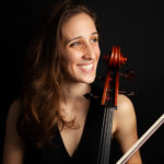 photo of a woman holding a cello and smiling off to the side