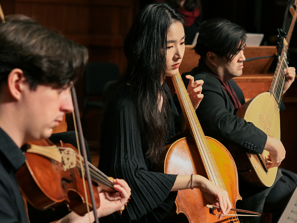 A trio of students play early music on string instruments.