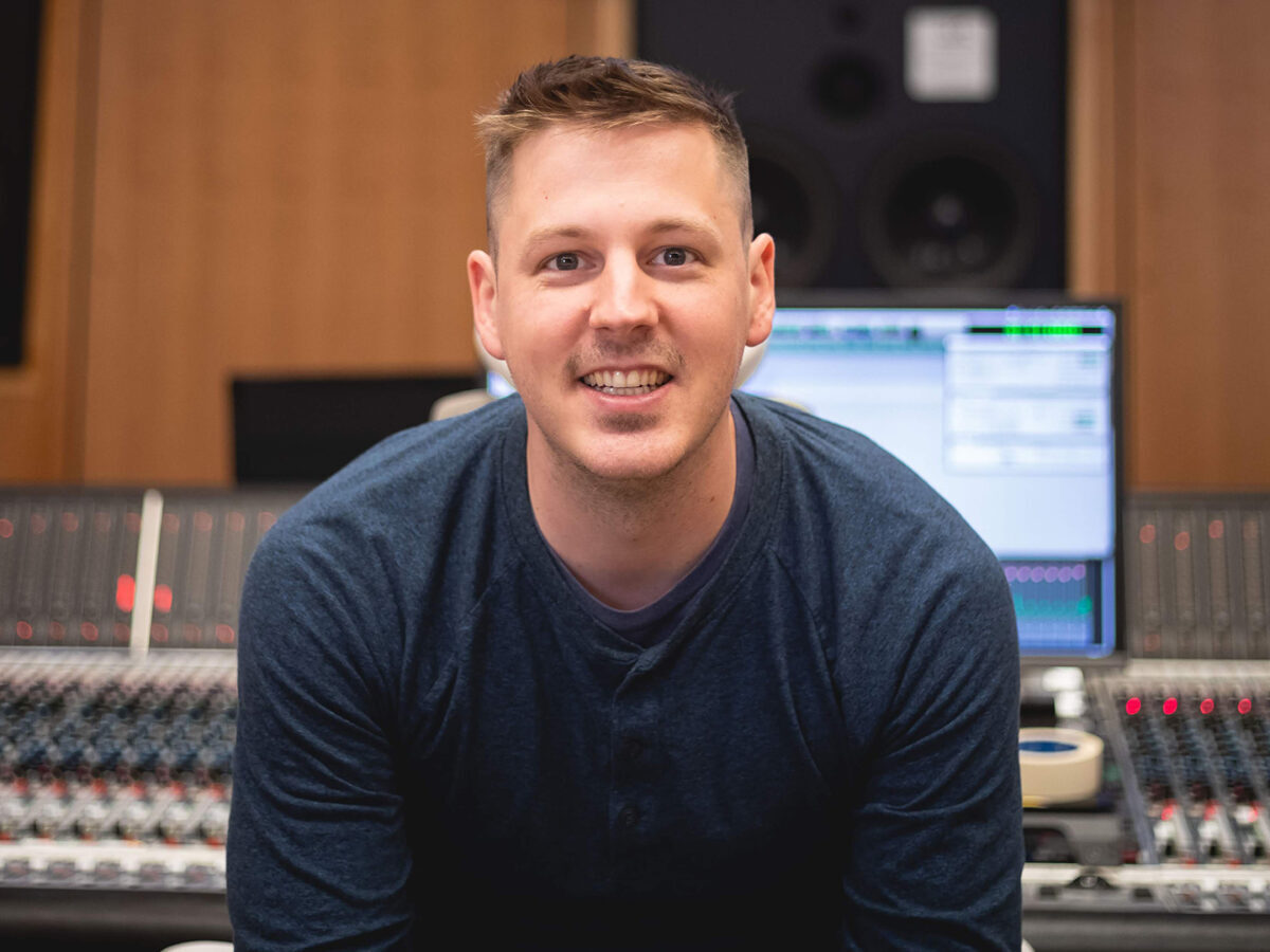 Headshot of Christian Amonson, sitting in front of a mixing board.