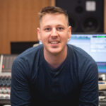 Headshot of Christian Amonson, sitting in front of a mixing board.