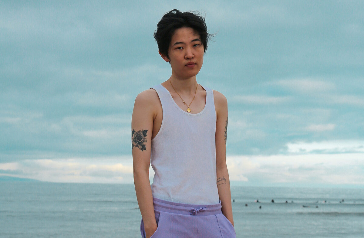 A musician stands in front of the ocean.