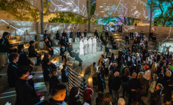 Singers perform outside with projected visuals.