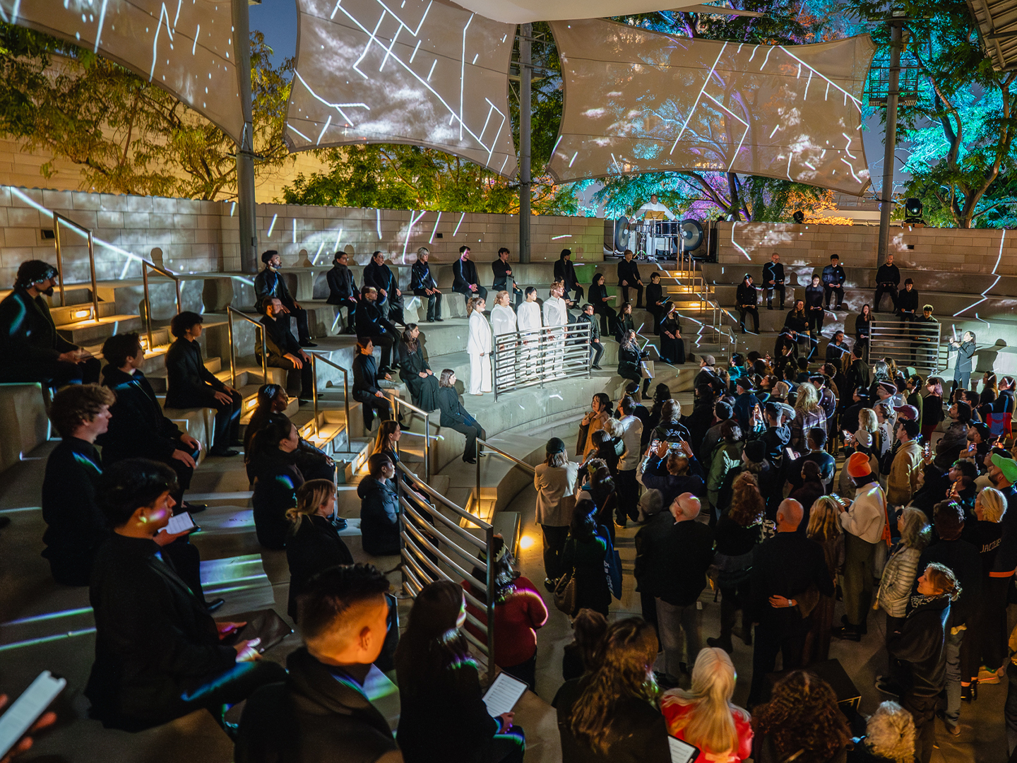 Singers perform outside with projected visuals.