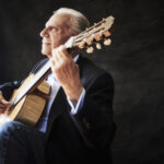Portrait of Pepe Romero, holding an acoustic guitar.