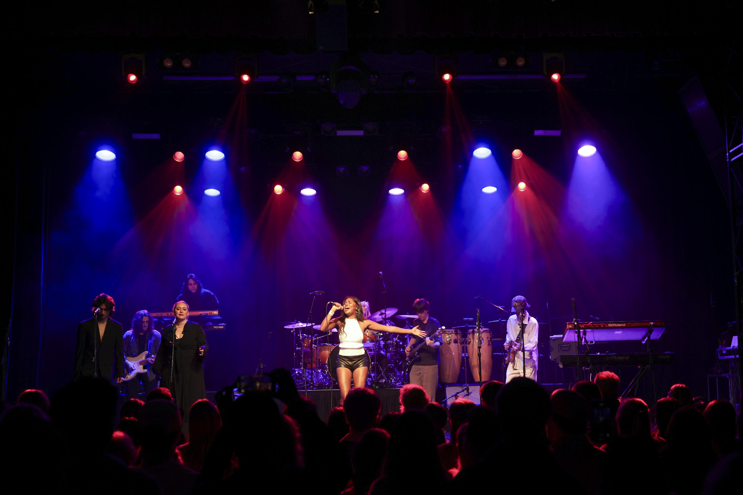 A singer is backed by their band onstage.