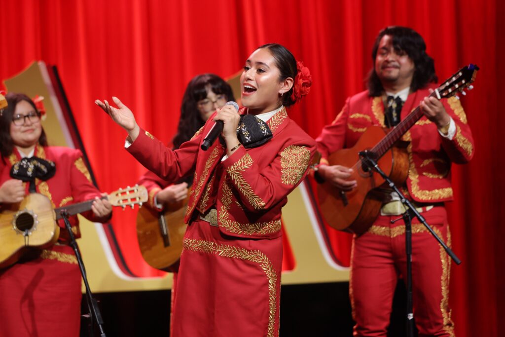A mariachi vocalist is foregrounded onstage.