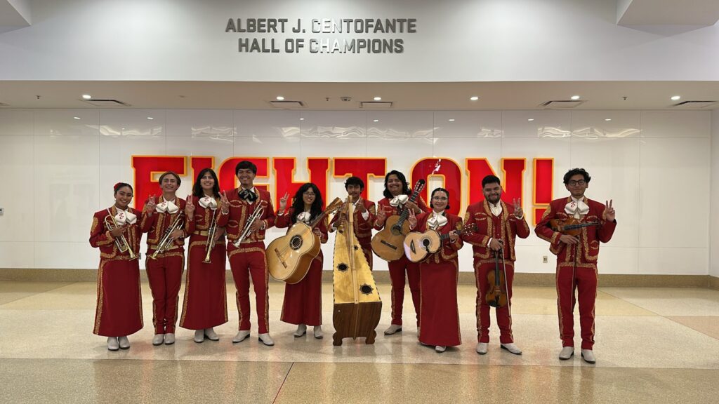 Los Troyanos pose in front of a mural, hiding their instruments.