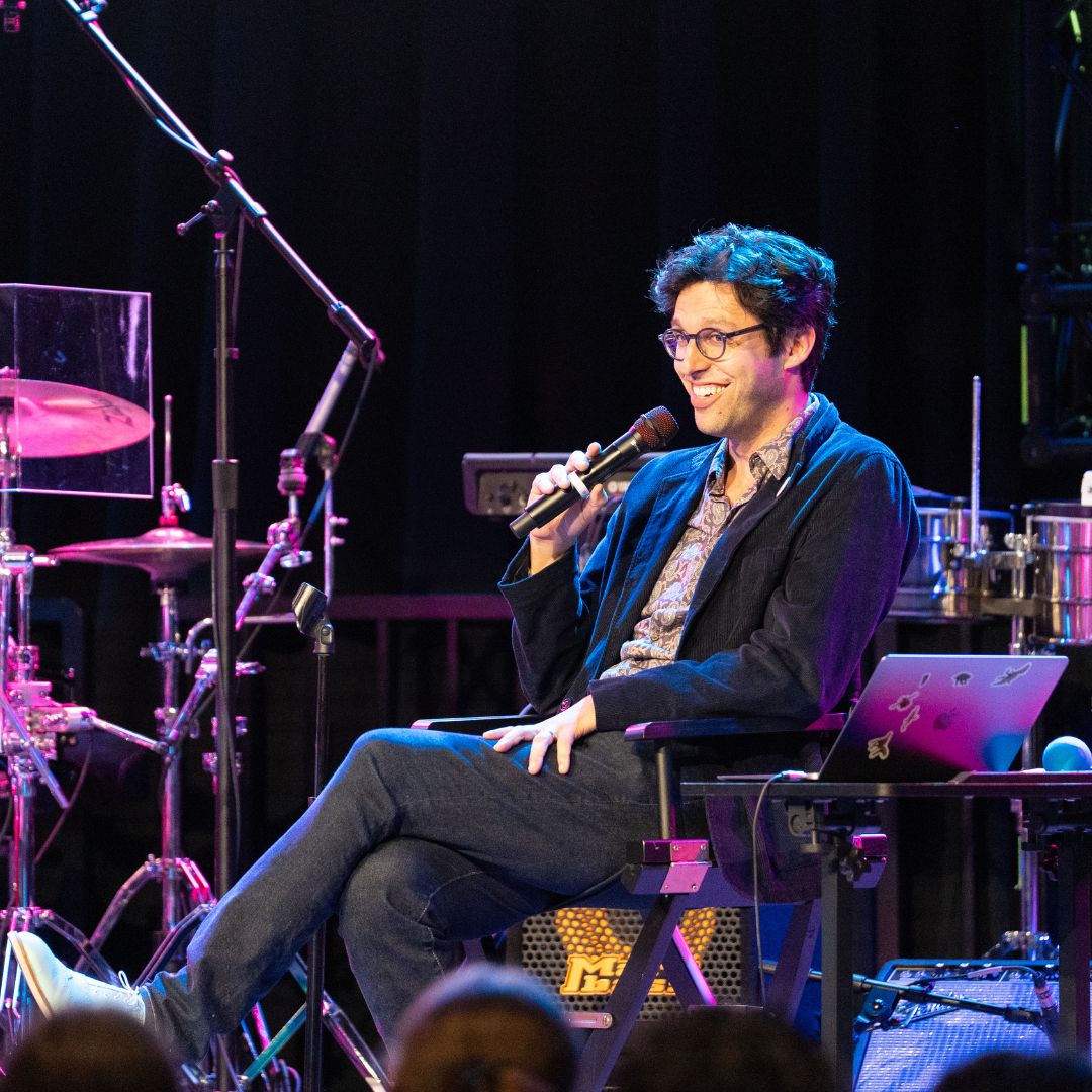 Nate Sloan conversing onstage with a microphone