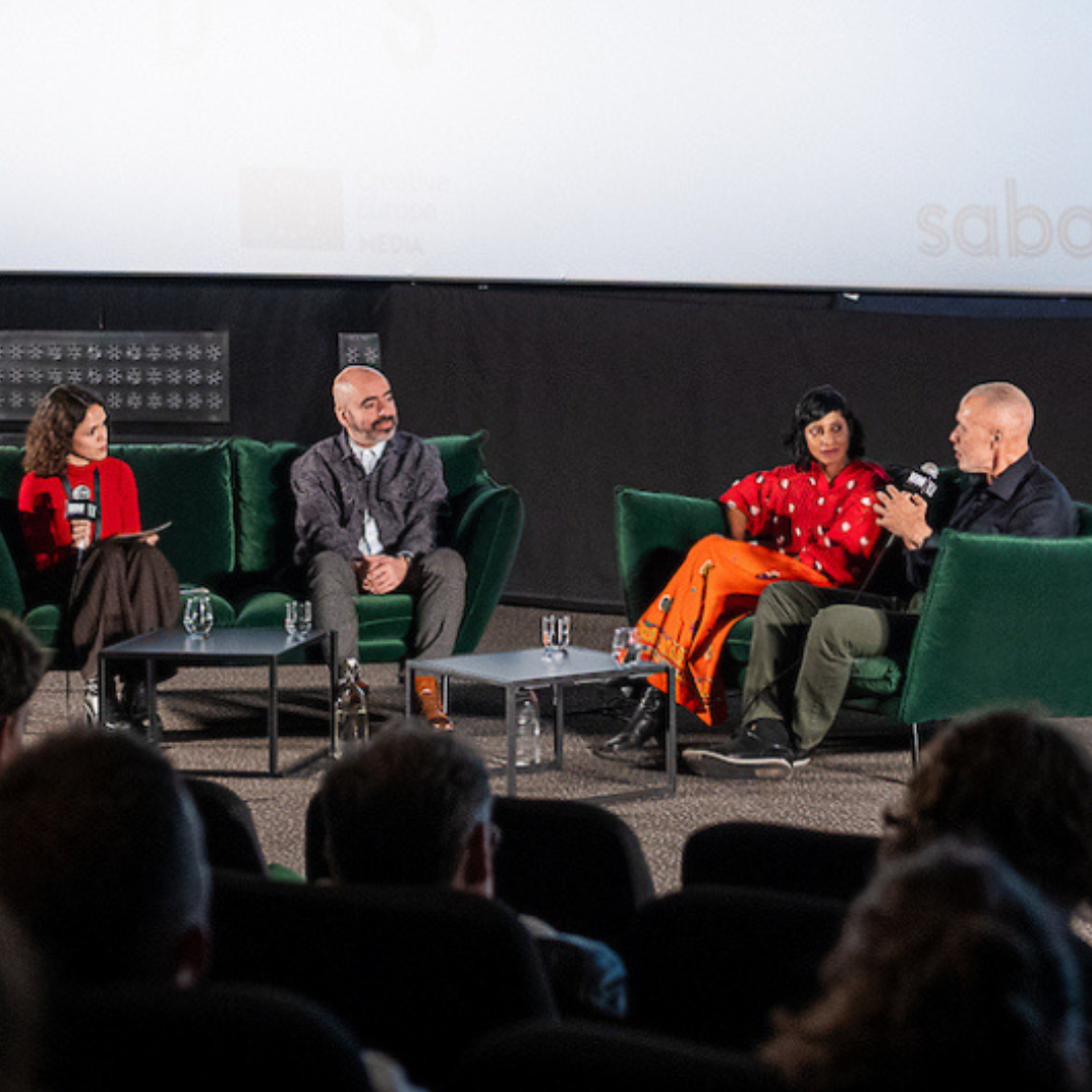 quartet of panelists conversing on plush couches