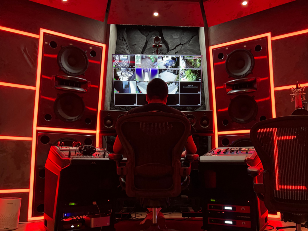 Man sits behind mixing console in music studio.