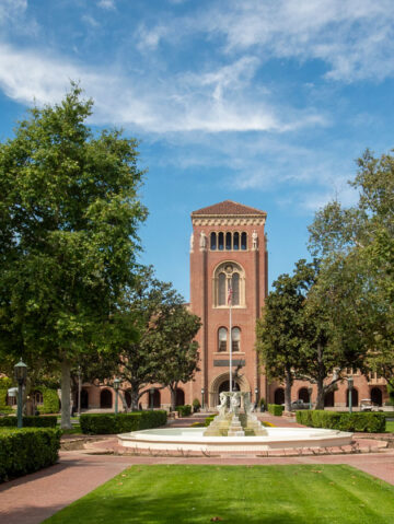 USC Bovard Auditorium exterior featuring lawn and fountain.