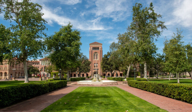 USC Bovard Auditorium exterior featuring lawn and fountain.