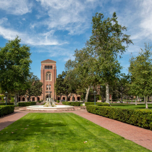 USC Bovard Auditorium exterior featuring lawn and fountain.