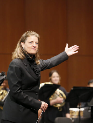 Conductor Sharon Lavery gestures to her ensemble for applause.