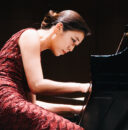 woman seated, playing piano.