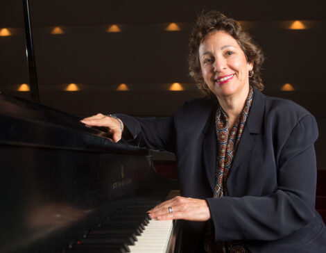 Dr. Iris Levine wearing a black blazer, seated at a piano.