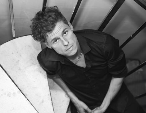 Sklar Funk seated on a staircase, looking up into the camera.