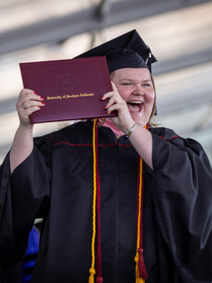 A Thornton graduate proudly holding up their diploma on commencement day.