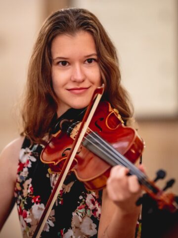 USC Thornton student playing the violin, seated.