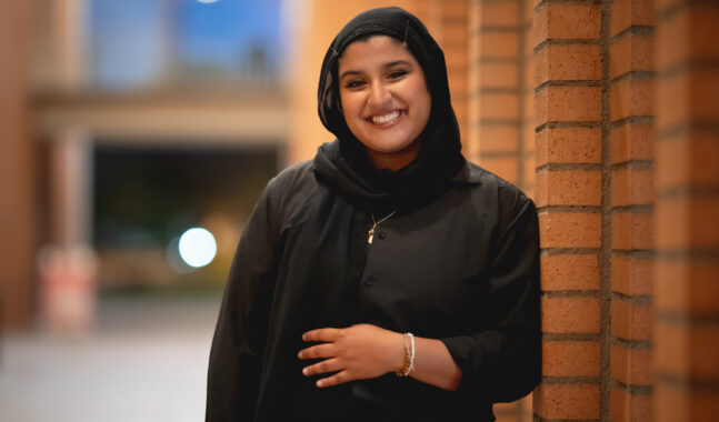 A USC Thornton choir member smiles for the camera, wearing a head scarf.