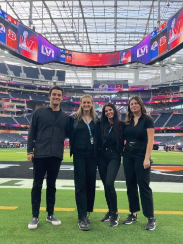 Music students and USC Thornton faculty member Sophie Reeves stand on a football field.