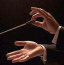 Image of two hands, one of them holding a conductor's baton.