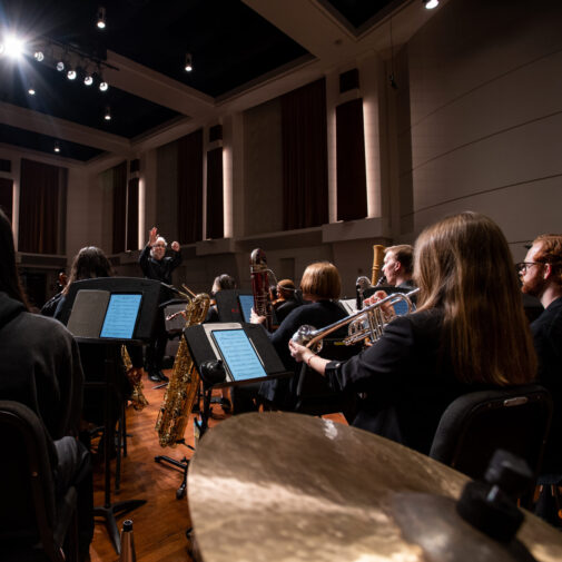 A professor conducts a mixed chamber ensemble onstage.