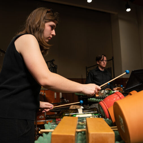 Student percussionist plays flower pots onstage.