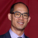 Image of man in a suit wearing glasses.