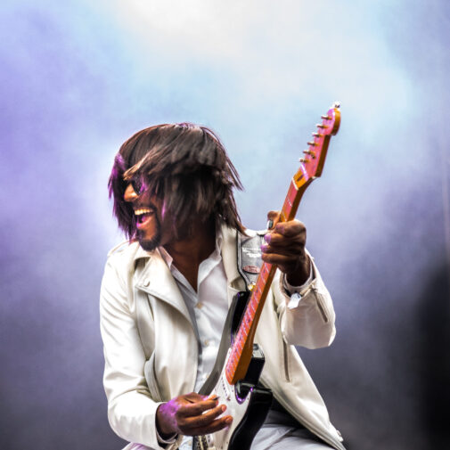 Kellindo Parker plays electric guitar onstage.
