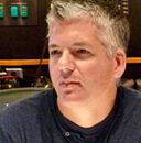 Michael Smith seated with a music console behind him.