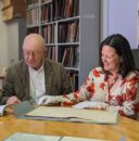 Polish Music Center scholars gather around documents on a table.