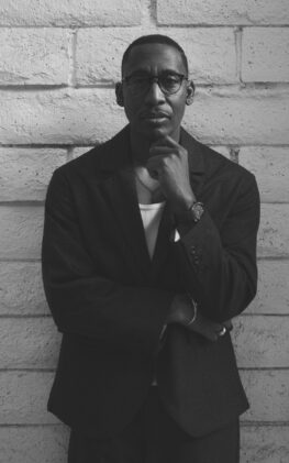Black and white photo of producer Raphael Saadiq leaning against a wall