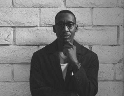 Black and white photo of producer Raphael Saadiq leaning against a wall