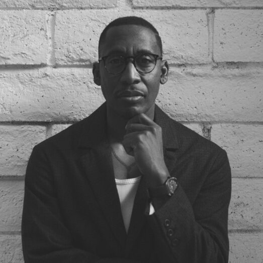 Black and white photo of producer Raphael Saadiq leaning against a wall