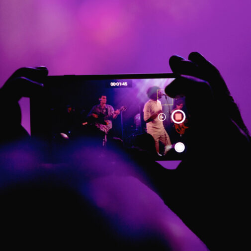 blurred hands looking at popular music performers through an iPhone.
