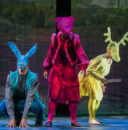 Scene from an opera, with three performers in animal-like costumes.