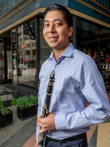 Javier Morales-Martinez holding a clarinet in front of a building in downtown Los Angeles.